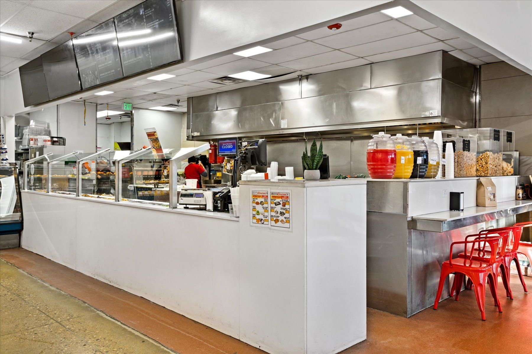 A restaurant with a long counter and stainless steel appliances.