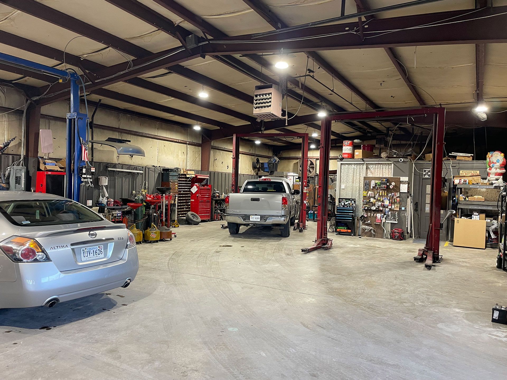 Interior of an auto repair shop with vehicles on lifts, tools, and equipment.