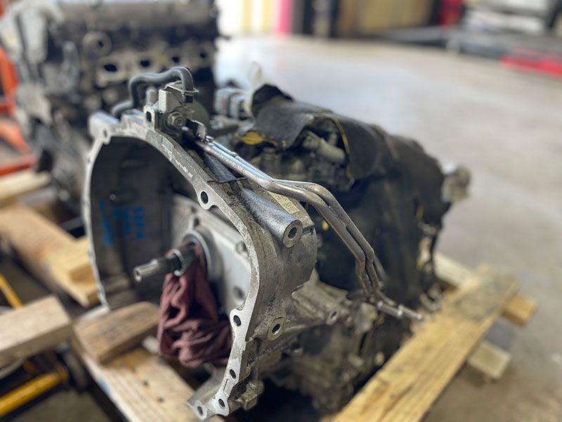 A used transmission and engine on a wooden pallet in a repair shop.
