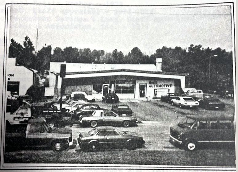 Automotive shop with cars parked in front. Sign reads 