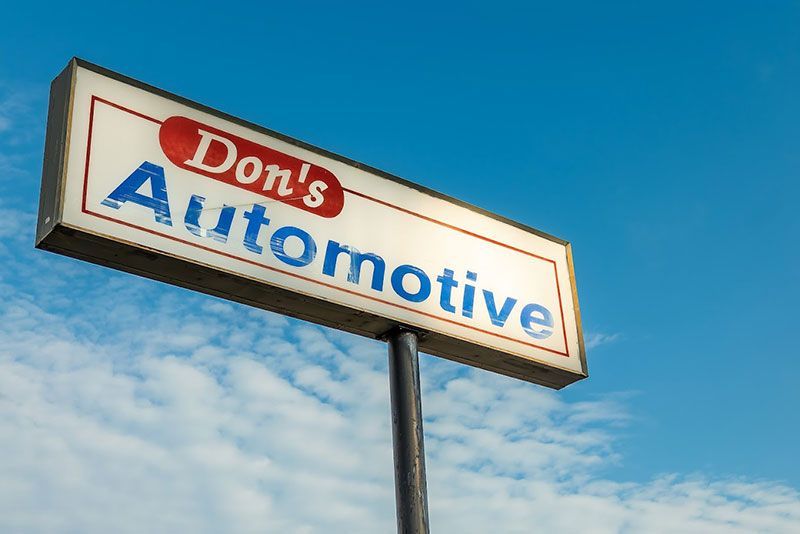 Sign for Don's Automotive: white and red sign with 
