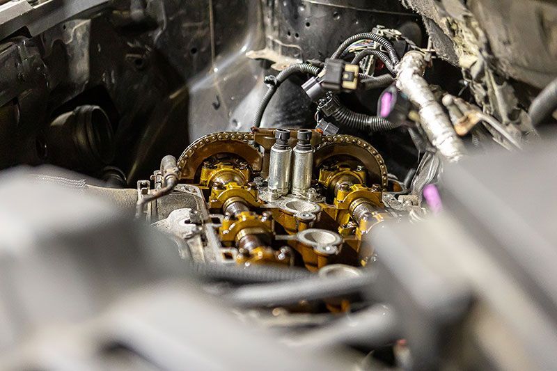 Engine components, visible camshafts and gears, inside a vehicle, in a workshop setting.