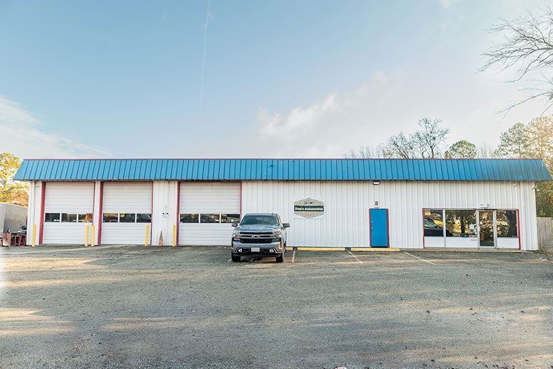Garage with blue roof and white walls. A truck is parked in front of the building.