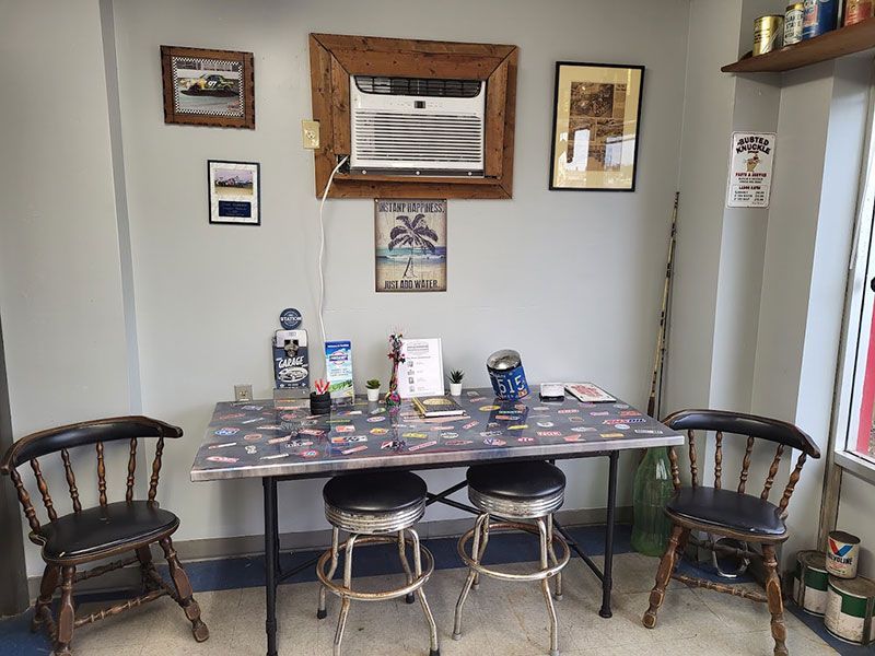 A small office area with a table, chairs, decorations, and an air conditioner.