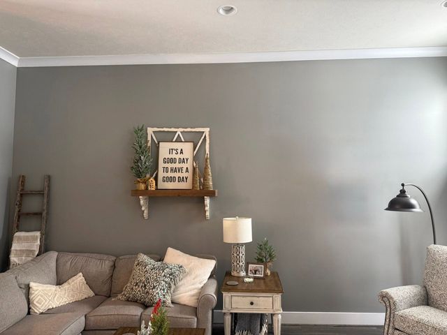 Cozy living room with gray walls, couch, lamp, side table, and wall shelf decor