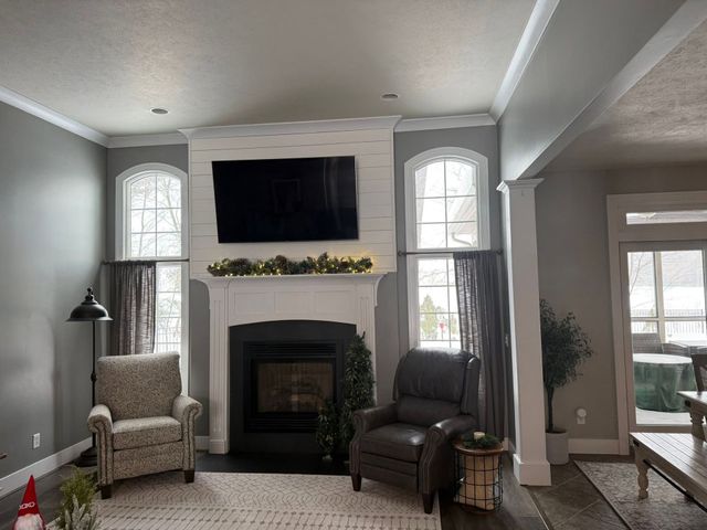 Bright living room with fireplace, TV, two armchairs, and large windows.