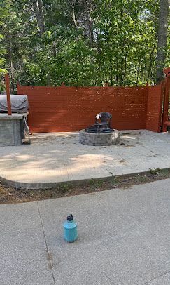 Small blue bottle on pavement near a fire hydrant and orange fence in a wooded area