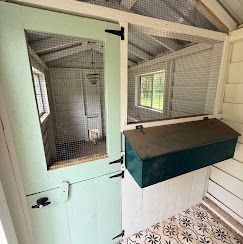 Small painted animal hutch with wire mesh doors inside a white porch or shed