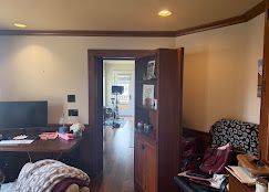 Living room with TV, desk, open door, and patterned chair beside a small table