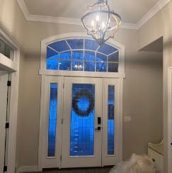 Front entryway with white double doors, blue glass sidelights, and a hanging light fixture