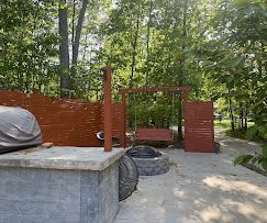 Red brick outdoor structure with a concrete platform and trees in a park-like setting