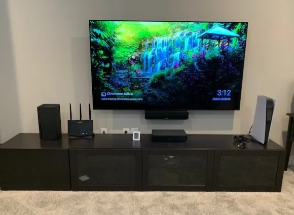 Living room media console with a wall-mounted TV displaying a colorful forest scene and two speakers on either side