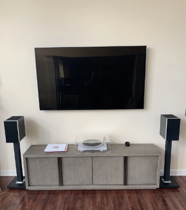 Living room TV wall with a console, turntable, and two black speakers