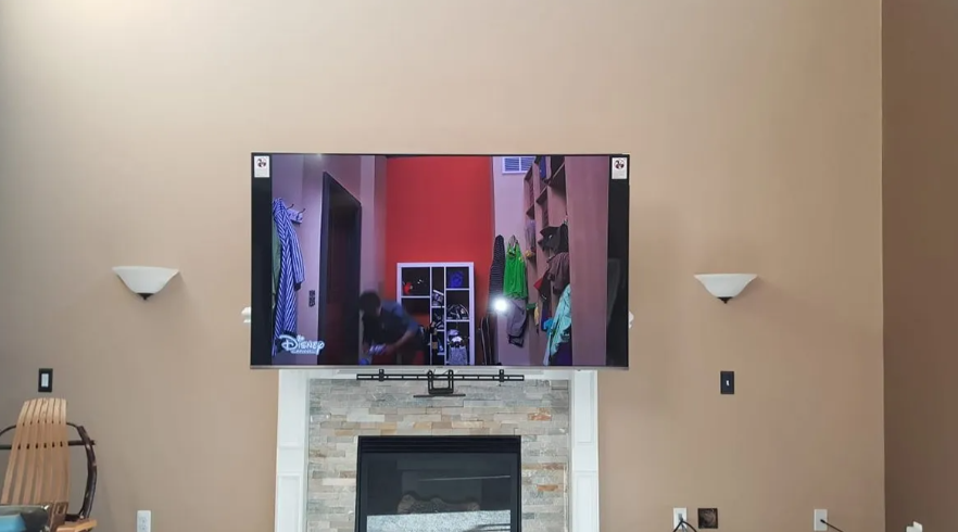 Wall-mounted TV above a fireplace in a beige living room, flanked by two wall sconces.