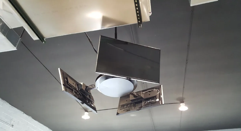 Damaged ceiling with a hanging black monitor, exposed panels, and recessed lights in a room