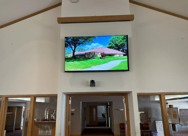 Church interior with a large wall-mounted screen displaying a bright outdoor landscape