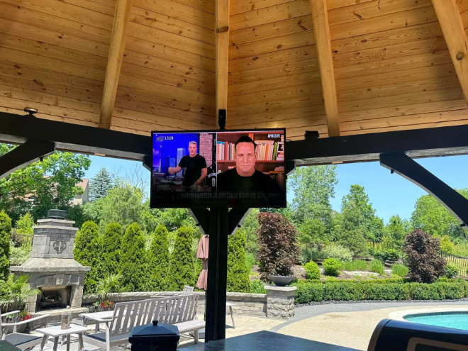 TV mounted under a wooden gazebo overlooking a garden and stone lantern