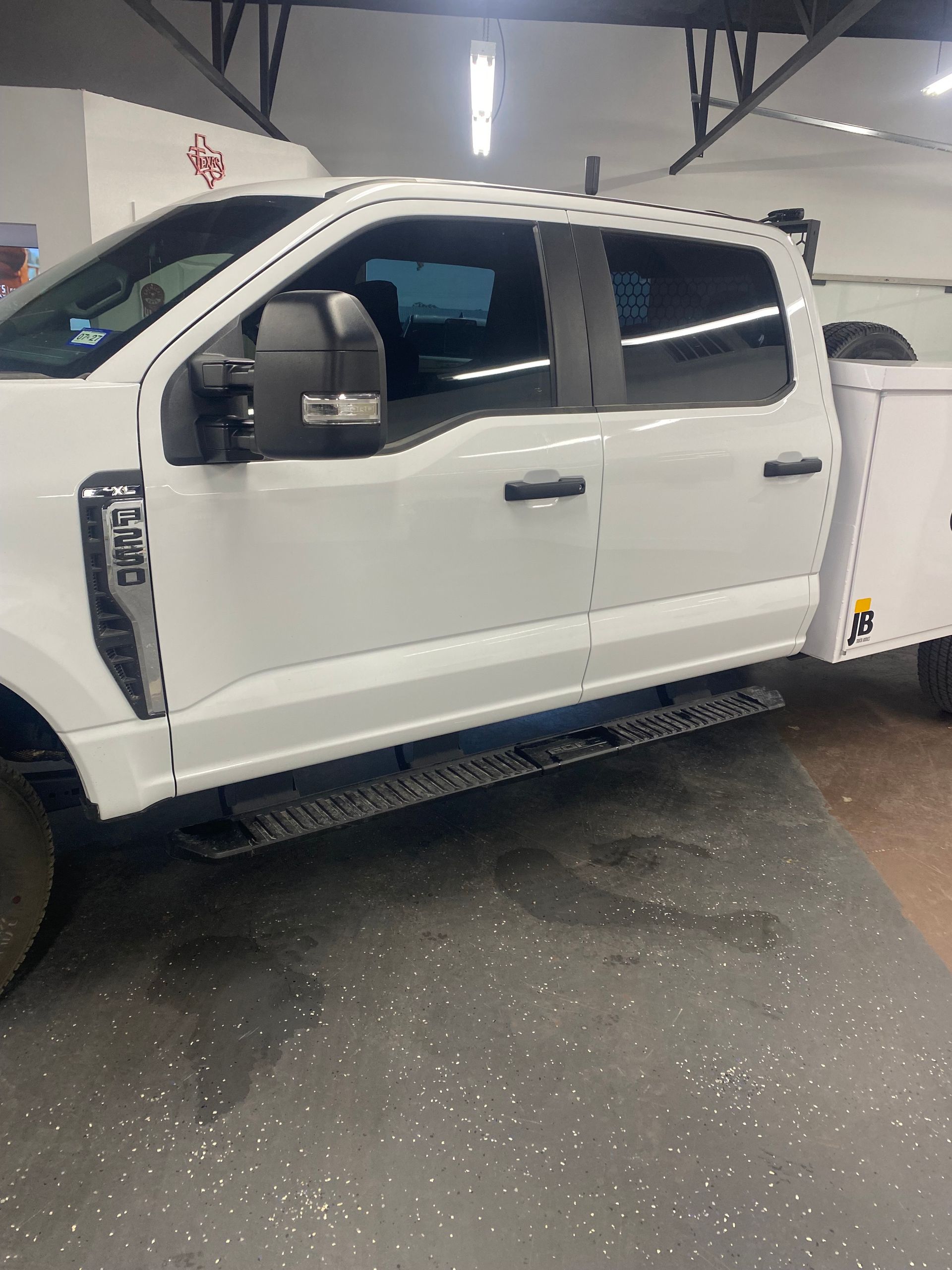 Red classic car with white stripes parked in front of a yellow building labeled