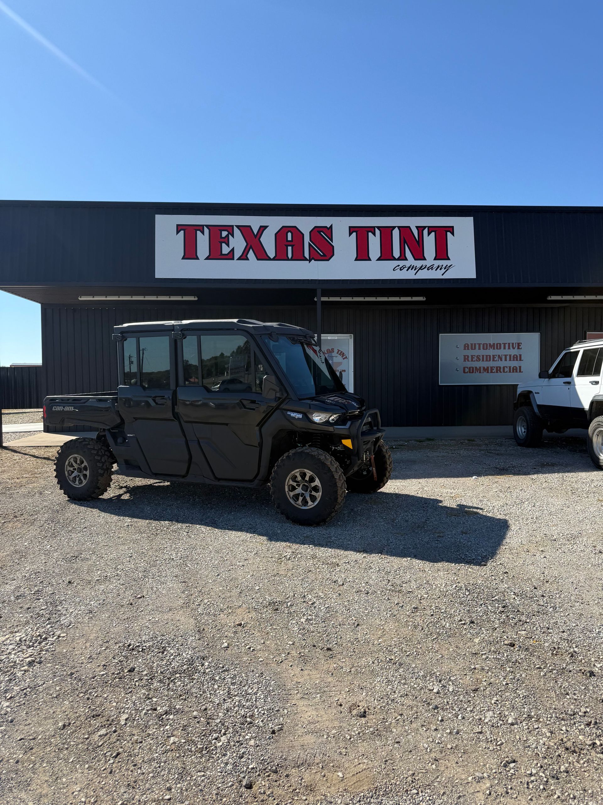 Storefront with large windows reflecting a parking lot and sky. Building has stone and brick exterior.