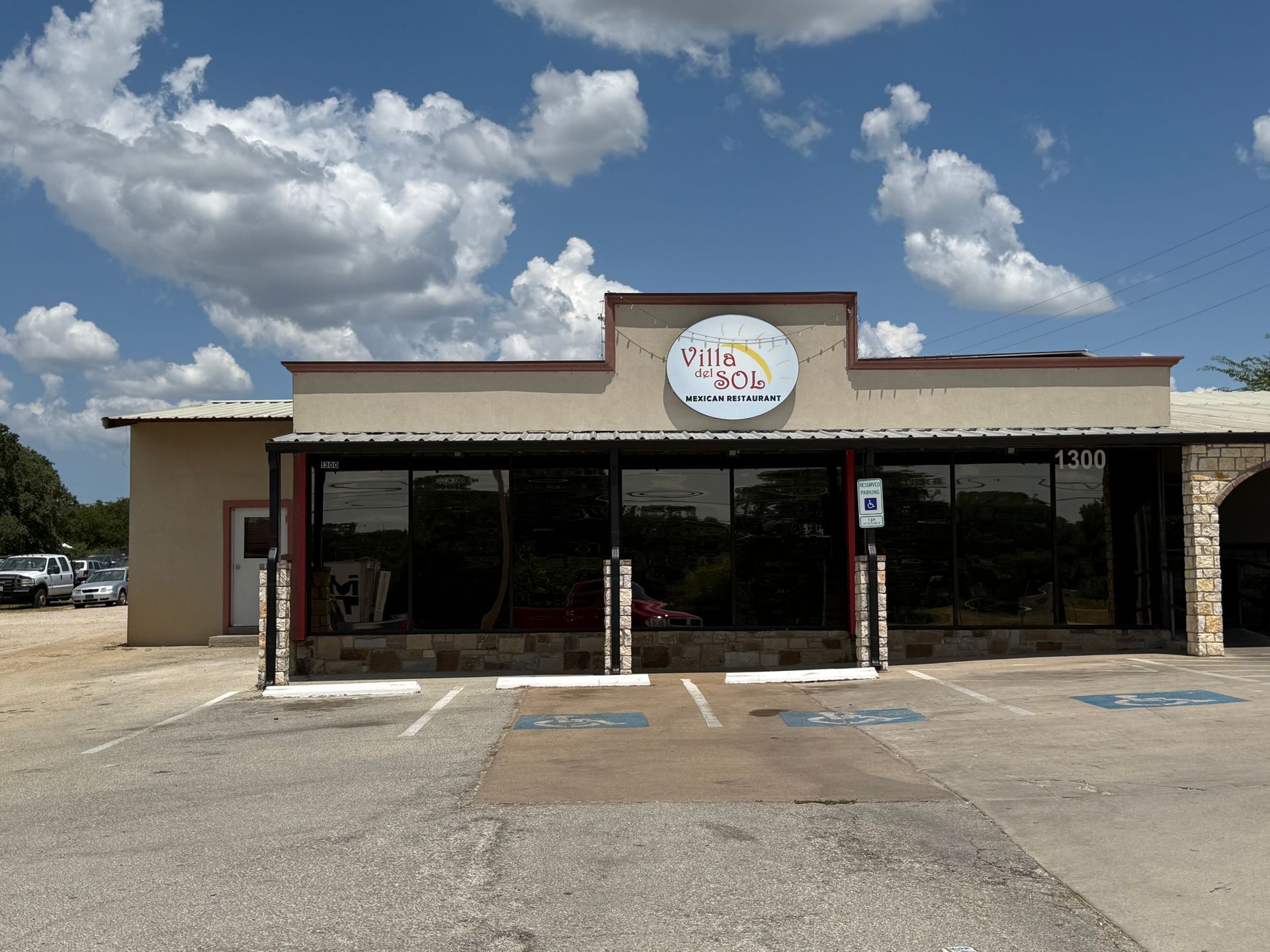 Exterior of a building with large windows, parking spaces, and a sign that reads 