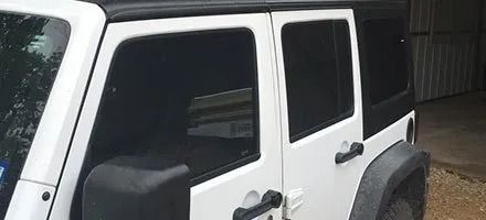 White Jeep SUV with black tinted windows and top, parked outdoors.