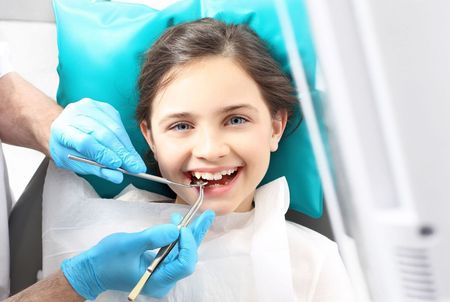 A woman is smiling while sitting in a dental chair.