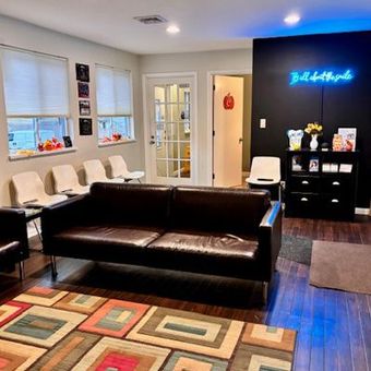 A waiting room with a couch , chairs , and a rug.