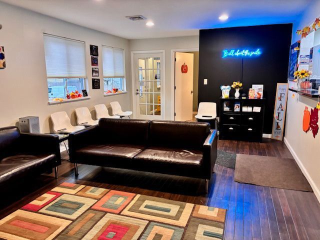 A waiting room with a couch , chairs and a rug.