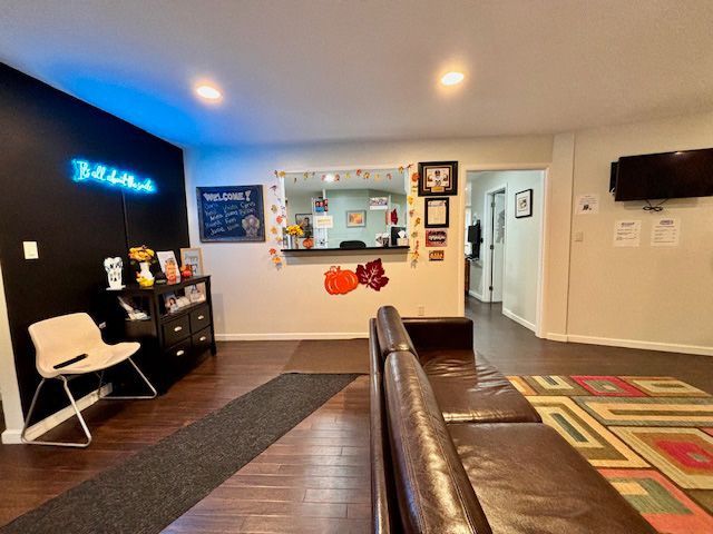 A living room with a couch and chair and a neon sign that says believe