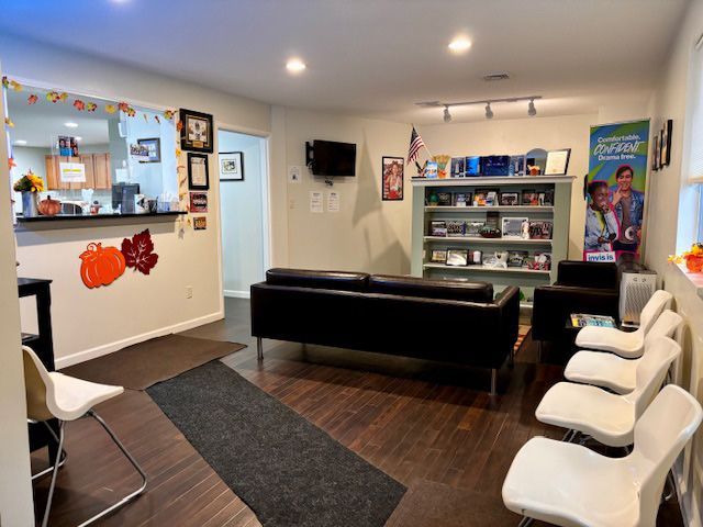 A waiting room with a couch , chairs and a tv.