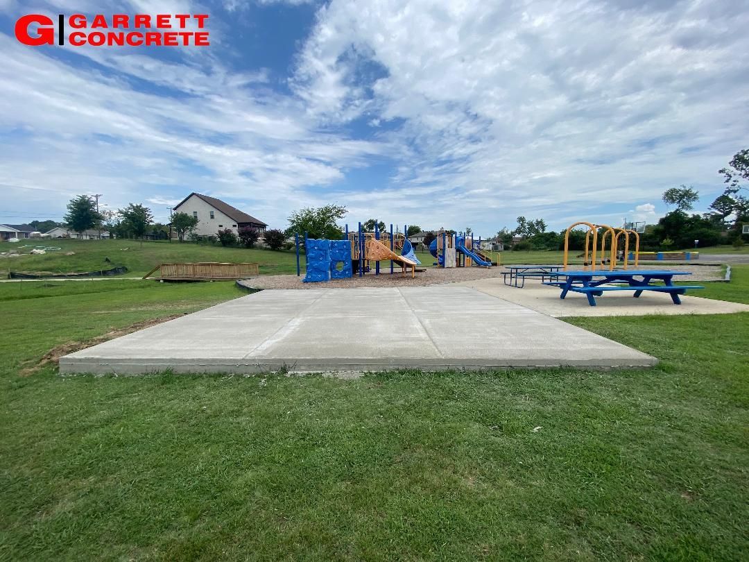 a playground in a park with a concrete platform in the middle of it .