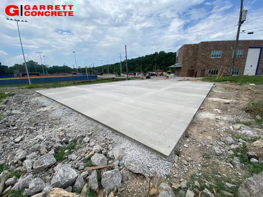 a large concrete slab is sitting in the dirt in front of a building
