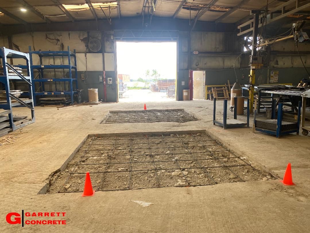 a large warehouse with a large hole in the floor and orange cones on the floor