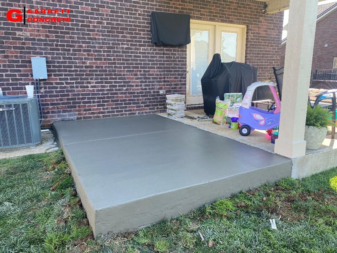 a concrete patio with a brick building in the background