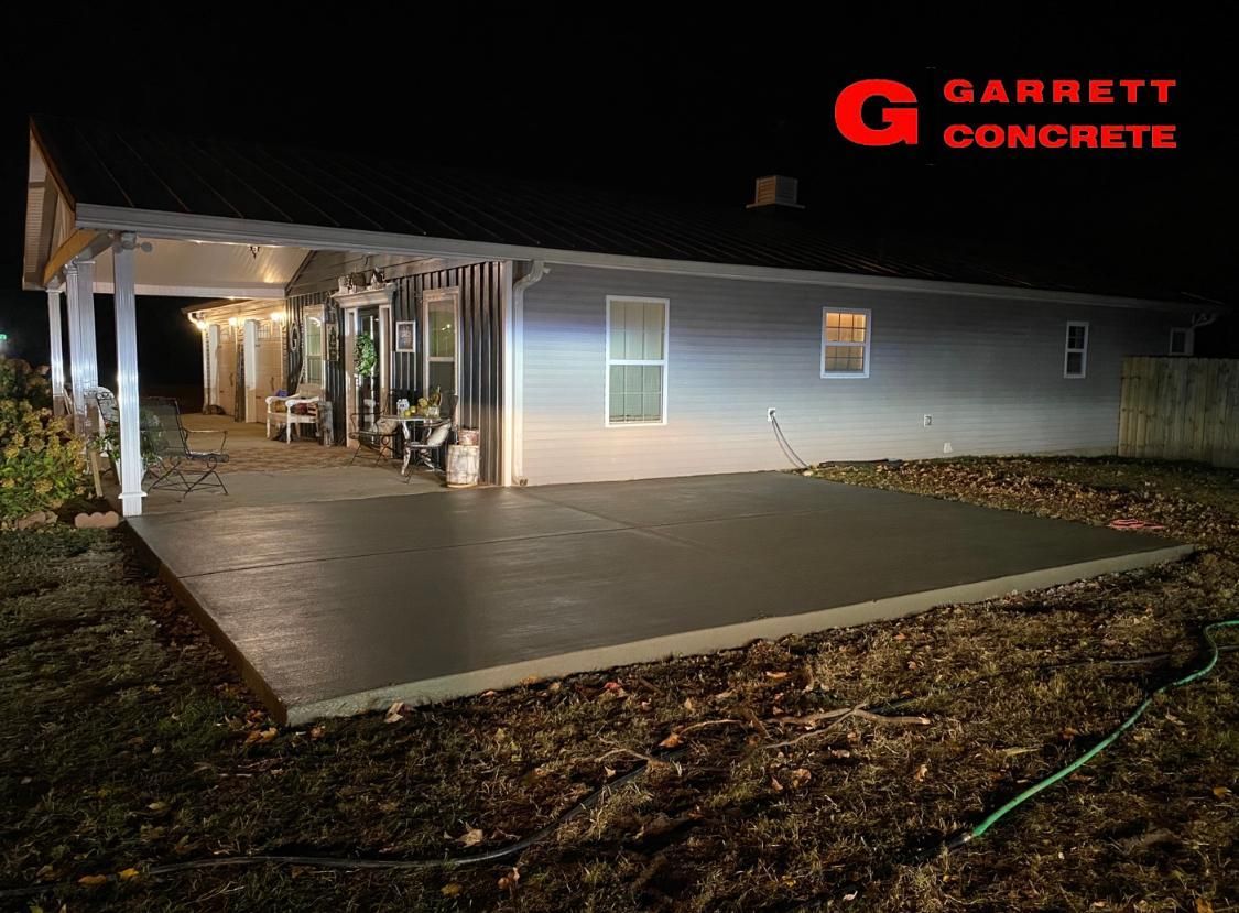 a house with a concrete patio in front of it is lit up at night
