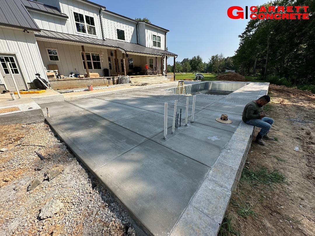 a man is sitting on a concrete patio in front of a house under construction