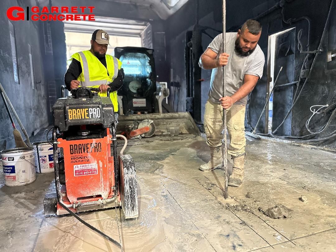 two men are working on a concrete floor in a garage