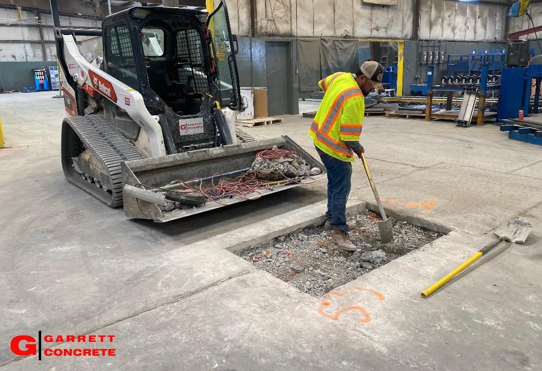 a man is digging a hole in the ground in front of a bulldozer