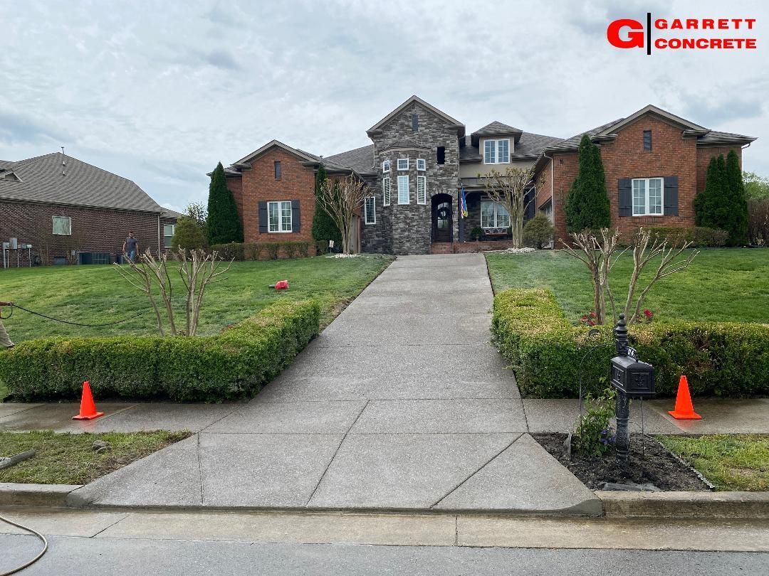 a large brick house with a concrete driveway in front of it