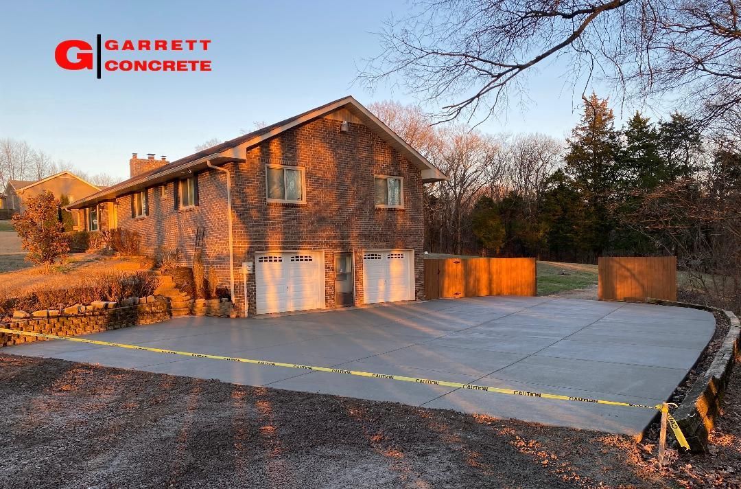 a brick house with a concrete driveway in front of it