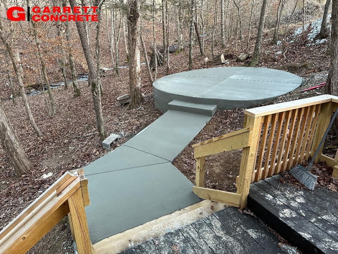 a concrete walkway leading to a wooden deck in the woods