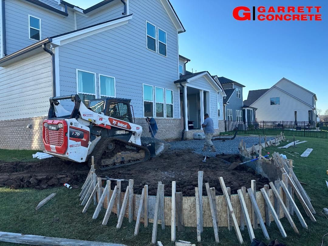 a bulldozer is digging a hole in front of a house