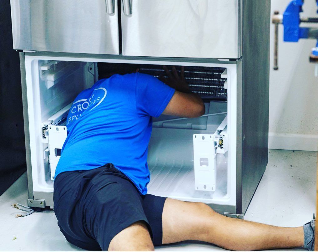 Person in blue shirt working on the interior of a refrigerator.