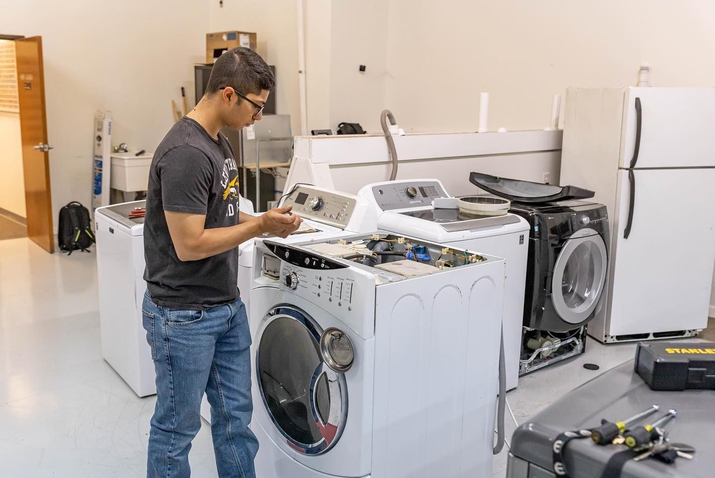 Five people wearing masks pose in front of a blue backdrop with graduation caps.