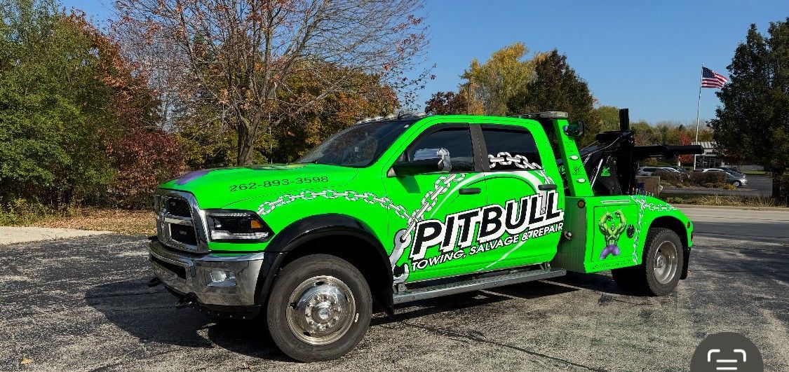 Green and black Pitbull towing truck parked outdoors.