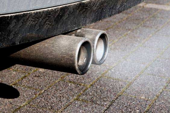 Exhaust pipes emitting fumes from a car on a brick surface.