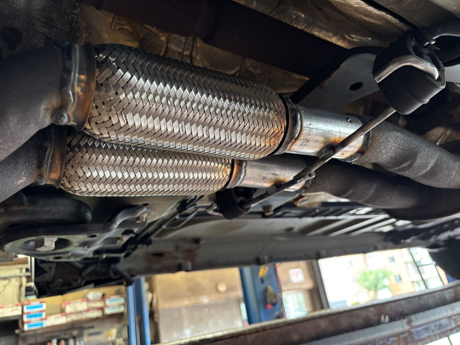 Undercarriage exhaust system with a flex pipe section, showing rust and repair.