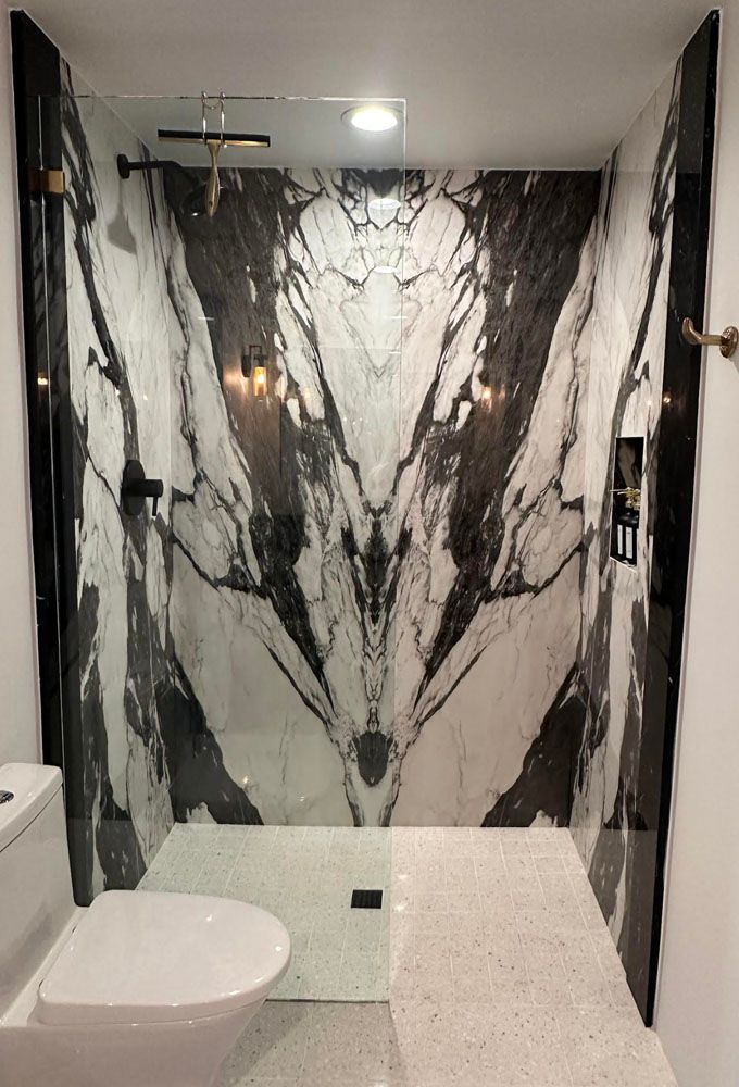 A bathroom with a toilet, shower and a large marble wall