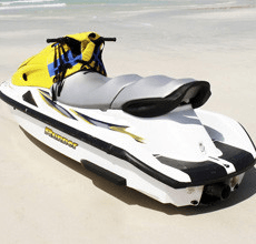 A white and yellow jet ski is parked on the beach.