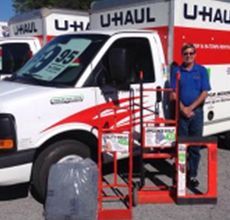 A man is standing in front of a uhaul truck.